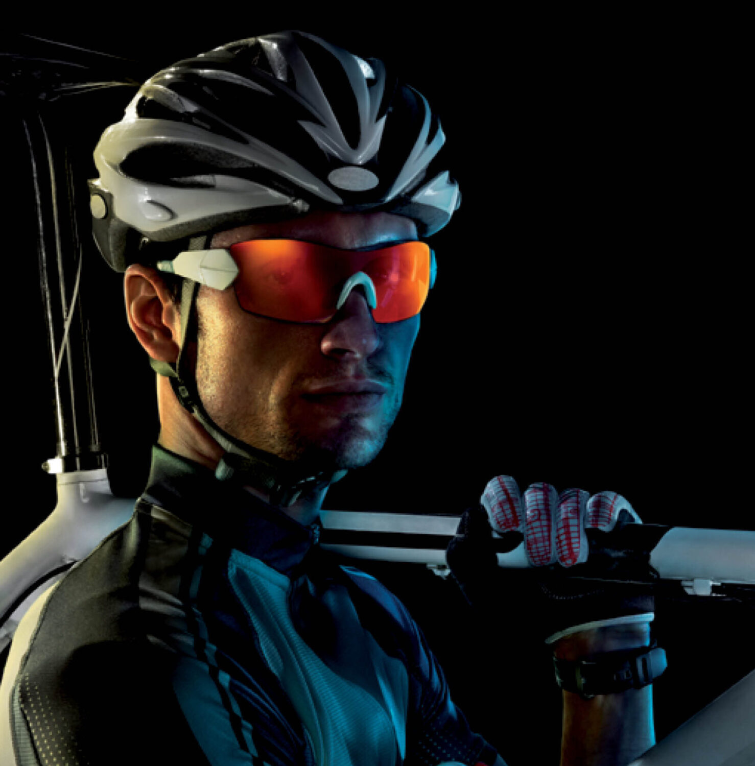 Radfahrer mit Helm und weißem Fahrrad trägt eine rote Revex Sport-Sonnenbrille vor schwarzem Hintergrund.