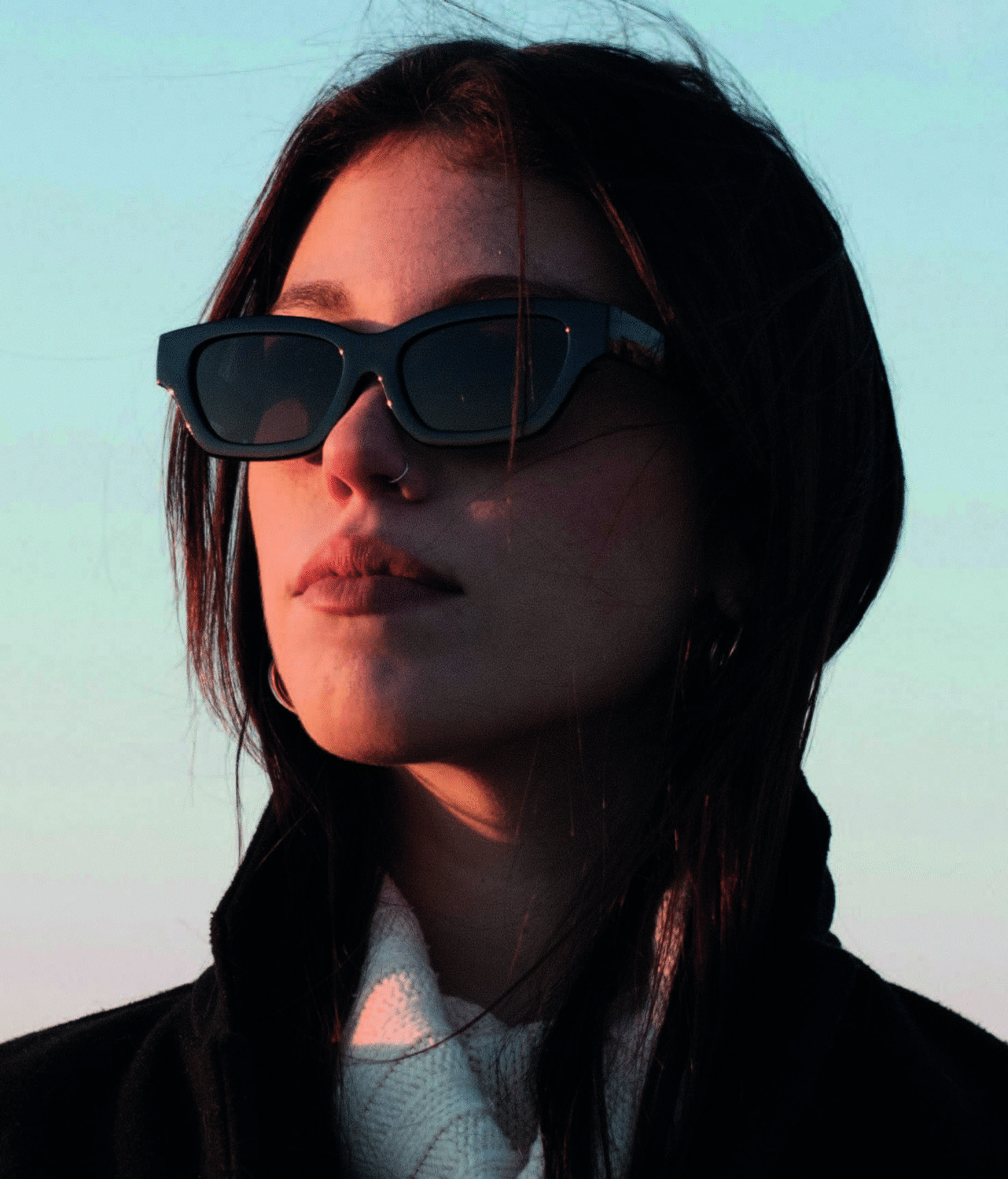 Frau mit stylischer schwarzer Sonnenbrille und polarisierten Gläsern bei Sonnenuntergang.