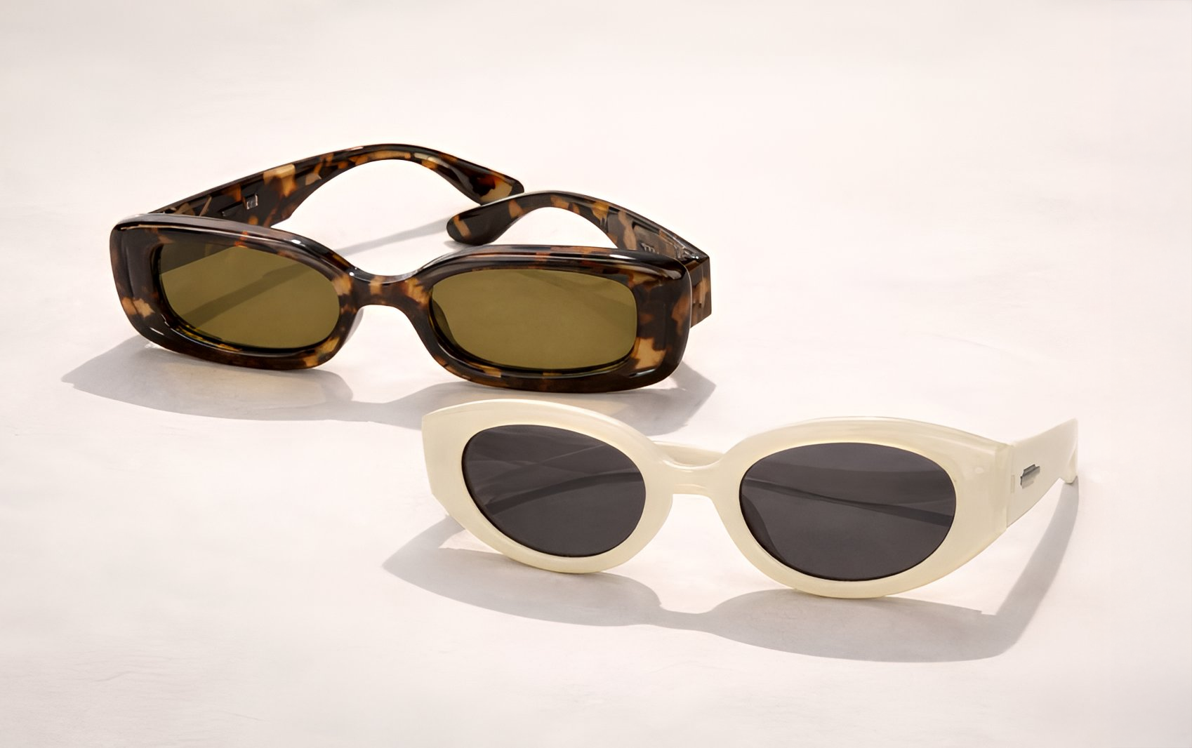 Deux lunettes de soleil tendance avec motif tortue et montures ovales blanches sur fond clair.