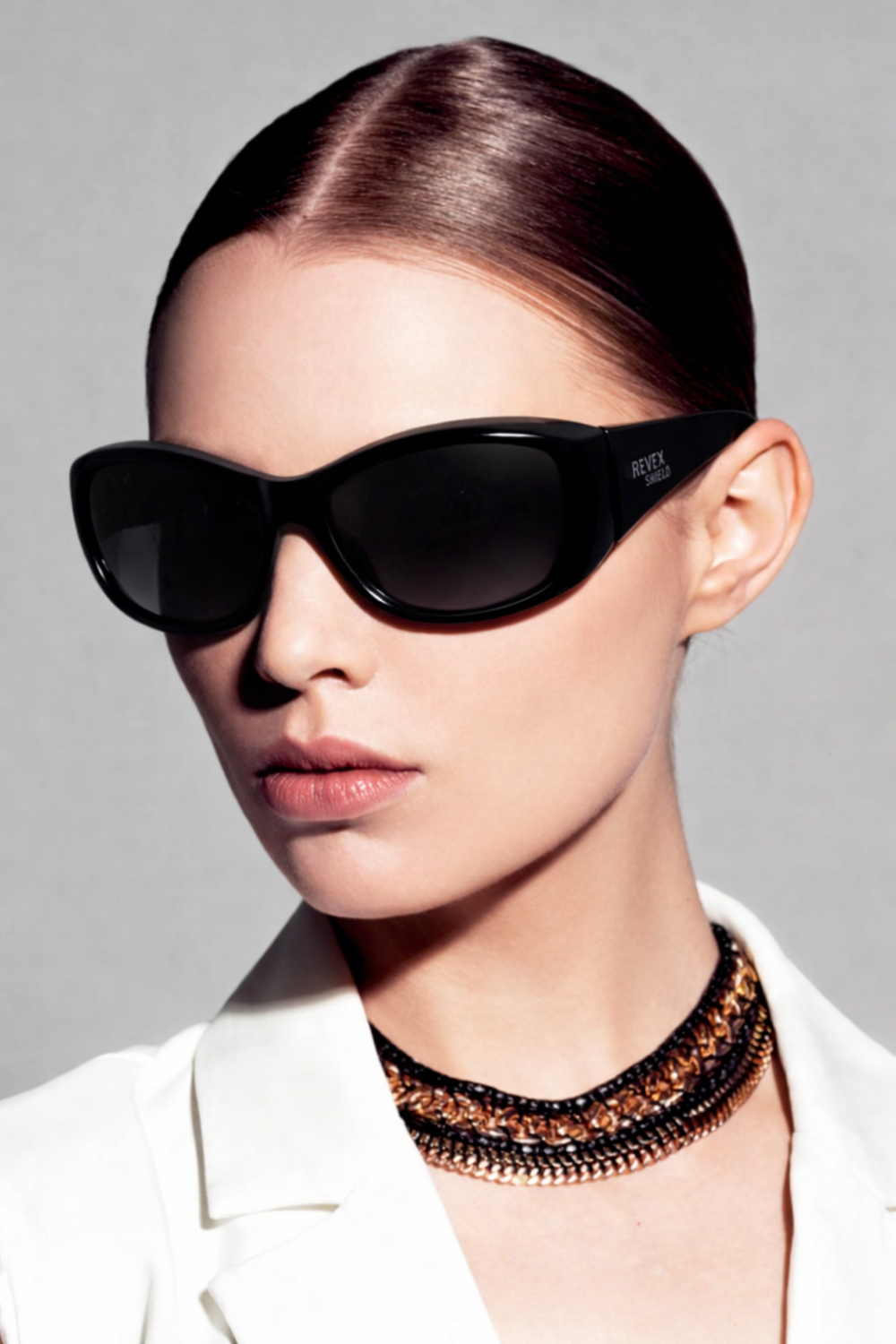 Una mujer con el pelo tirante lleva unas gafas sobregafas Revex negras sobre sus gafas normales.